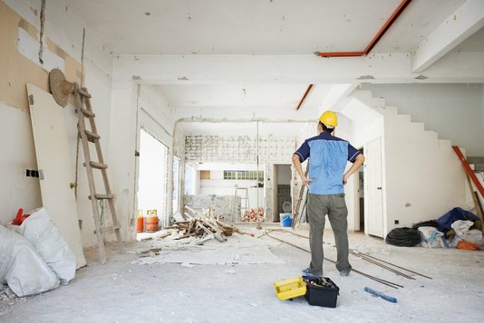 Handwerker betrachtet den Rohbau von innen.